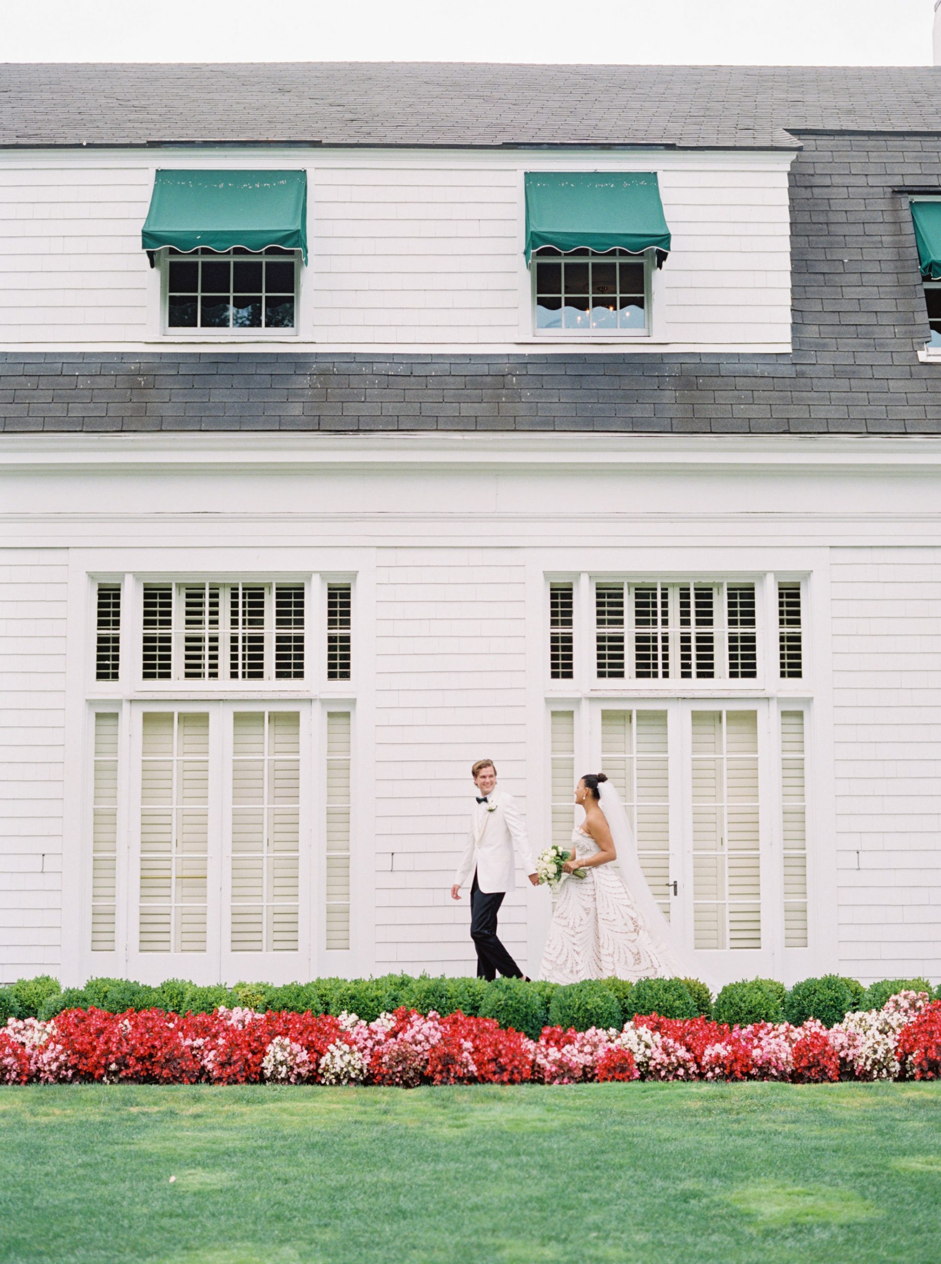 Bride and groom walking in front of Waverley Country Club in Portland OR. Captured by global destination wedding photographer Carlos Hernandez